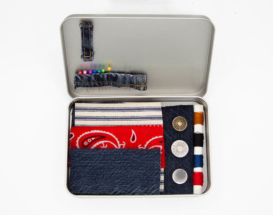 sewing kit in a metal tin including needles, pins, fabric patches, thread, and buttons. 